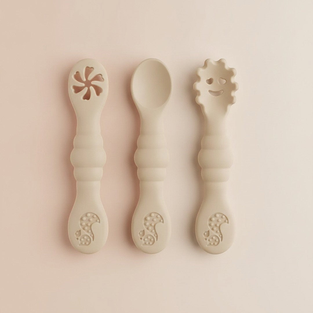DearXime 3-piece beige silicone baby utensil set with ergonomic handles, including a slotted spoon, spoon, and fork.