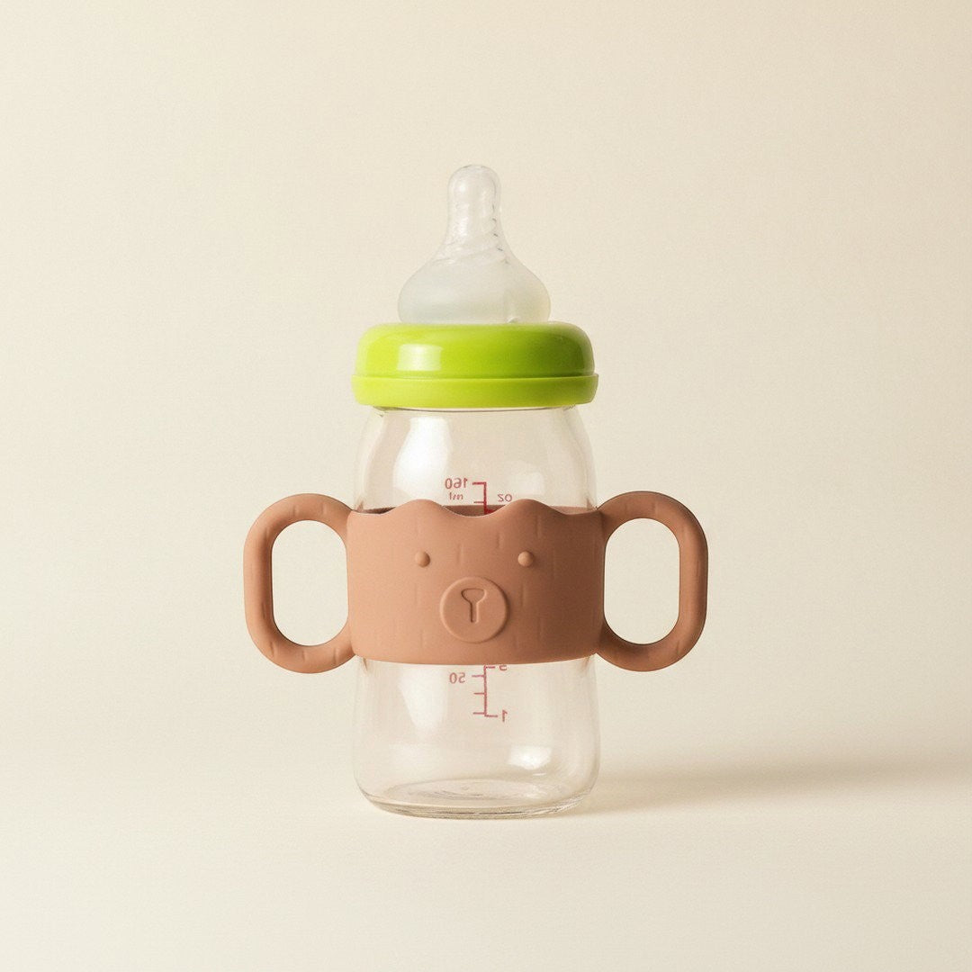 DearXime brown silicone baby bottle handle with a cute bear face design attached to a clear glass bottle
