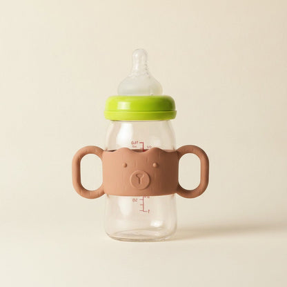 DearXime brown silicone baby bottle handle with a cute bear face design attached to a clear glass bottle
